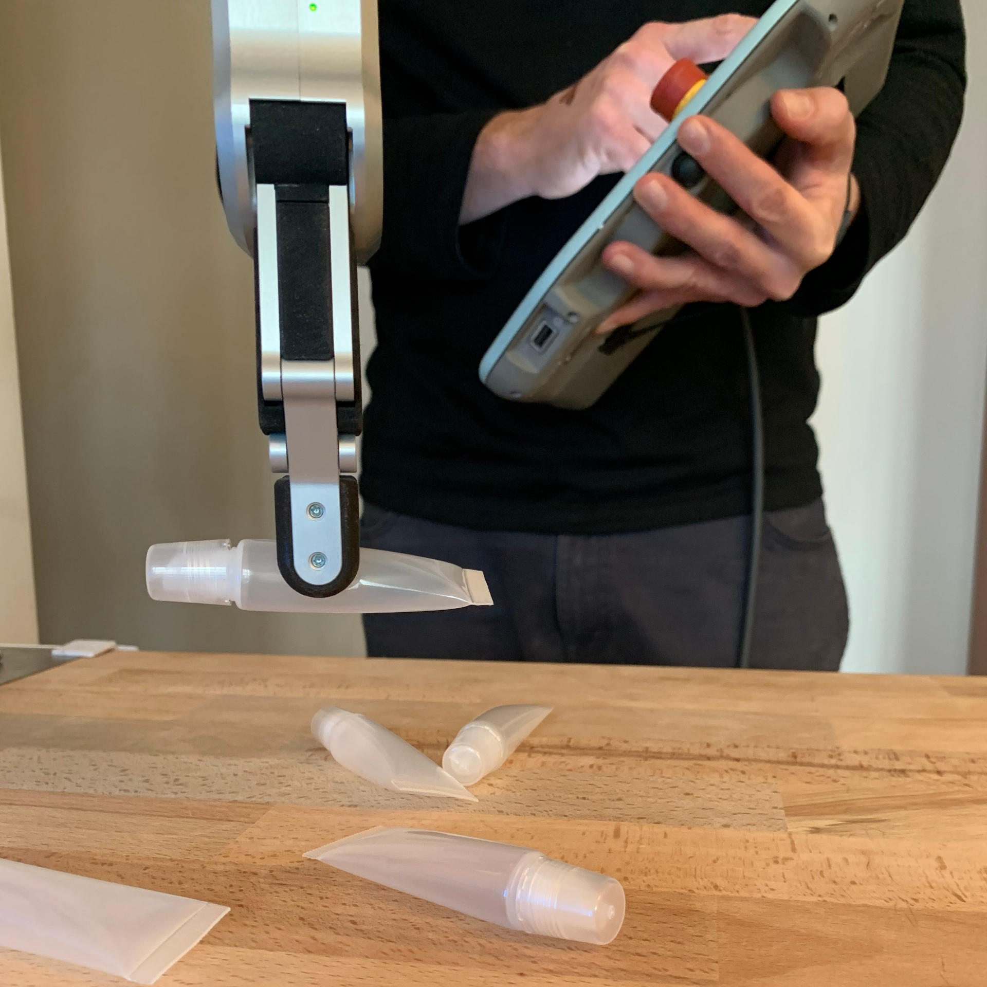 Engineer programming a robot arm gripping a deformable tube during installation